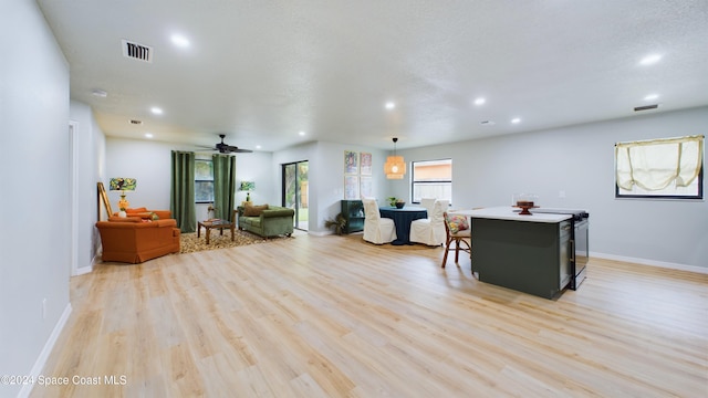 living room featuring a textured ceiling, light hardwood / wood-style floors, and ceiling fan