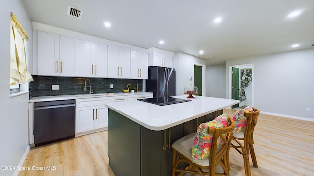 kitchen featuring a center island, black appliances, white cabinets, sink, and light hardwood / wood-style flooring