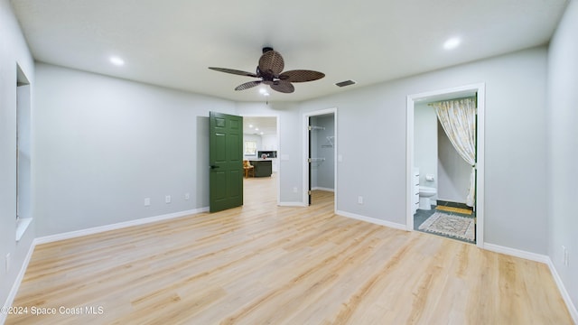 unfurnished bedroom featuring connected bathroom, a spacious closet, ceiling fan, a closet, and light wood-type flooring