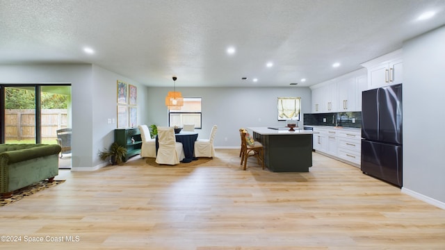 kitchen featuring black fridge, plenty of natural light, and white cabinets