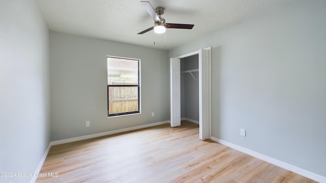 unfurnished bedroom with ceiling fan, a closet, light hardwood / wood-style floors, and a textured ceiling