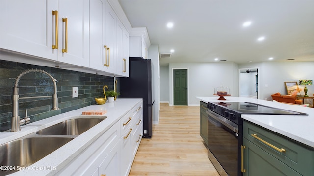 kitchen featuring white cabinetry, sink, tasteful backsplash, light hardwood / wood-style flooring, and stainless steel range with electric stovetop