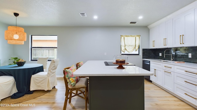 kitchen with white cabinets, decorative light fixtures, and light wood-type flooring