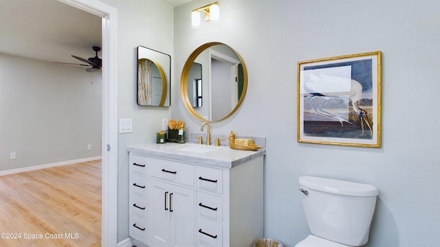 bathroom with hardwood / wood-style floors, vanity, toilet, and ceiling fan