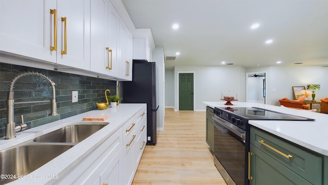 kitchen with electric range, sink, decorative backsplash, white cabinets, and light wood-type flooring