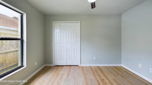 unfurnished bedroom featuring a closet, light hardwood / wood-style flooring, multiple windows, and ceiling fan