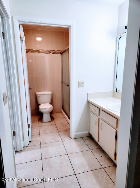 bathroom with tile patterned flooring, a shower stall, vanity, and toilet