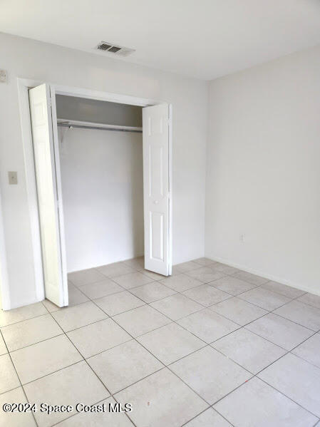 unfurnished bedroom with a closet, visible vents, and light tile patterned floors