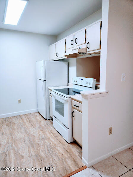 kitchen featuring white appliances, baseboards, white cabinets, light countertops, and under cabinet range hood