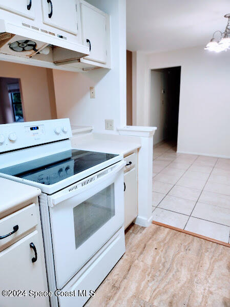 kitchen featuring light countertops, white range with electric cooktop, white cabinetry, and under cabinet range hood