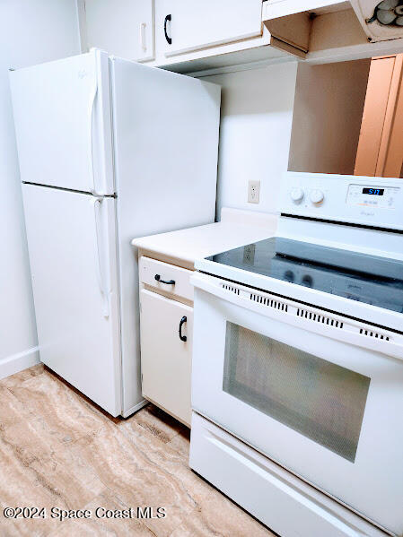 kitchen featuring white appliances, light countertops, light wood-style flooring, and white cabinets