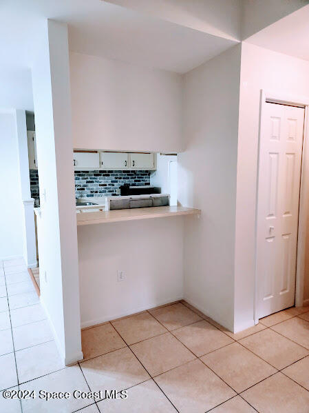 kitchen with light tile patterned floors, light countertops, and backsplash