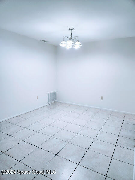 unfurnished room featuring a chandelier, visible vents, and baseboards