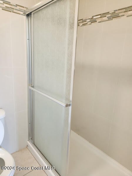 full bath featuring a shower stall, toilet, and tile walls