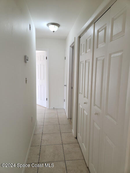 hall featuring light tile patterned floors and baseboards