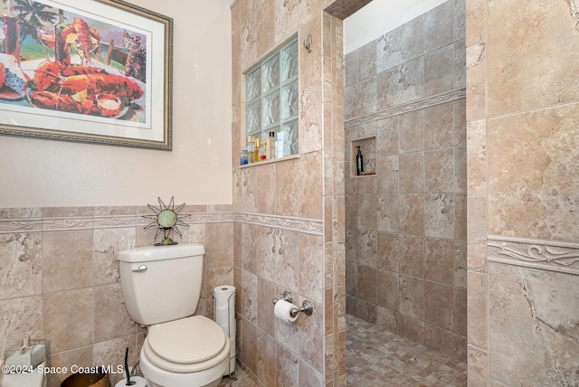 bathroom featuring a tile shower, toilet, and tile walls