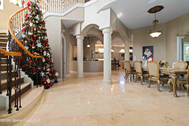 dining space with decorative columns, a high ceiling, and an inviting chandelier