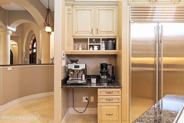 kitchen featuring dark stone counters, light tile patterned flooring, cream cabinets, and built in refrigerator