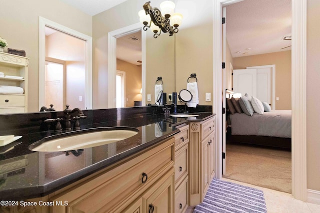 ensuite bathroom featuring double vanity, a notable chandelier, a sink, and ensuite bathroom