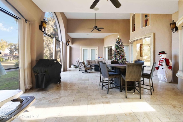 dining area featuring ceiling fan and a towering ceiling