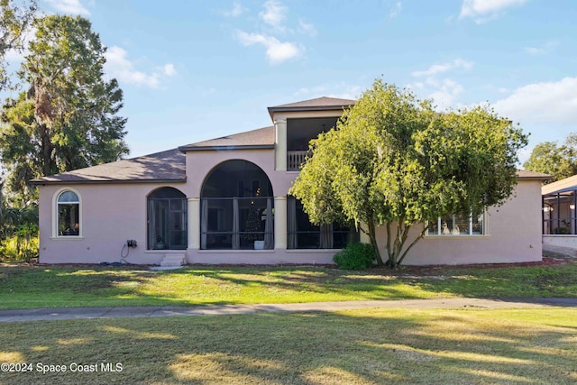 rear view of house featuring a lawn and stucco siding