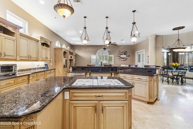 kitchen featuring hanging light fixtures, light brown cabinets, a sink, and a center island