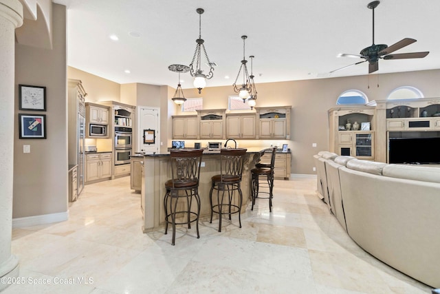 kitchen featuring stainless steel appliances, open floor plan, an island with sink, a kitchen breakfast bar, and baseboards