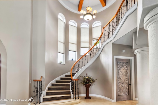 staircase with a chandelier, arched walkways, a high ceiling, and baseboards