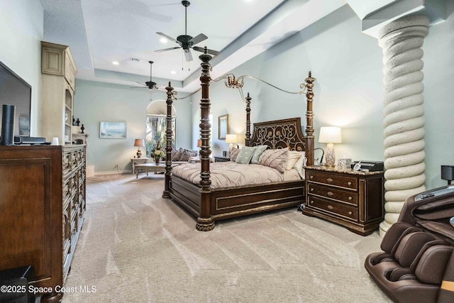 bedroom with a tray ceiling, light carpet, decorative columns, and recessed lighting