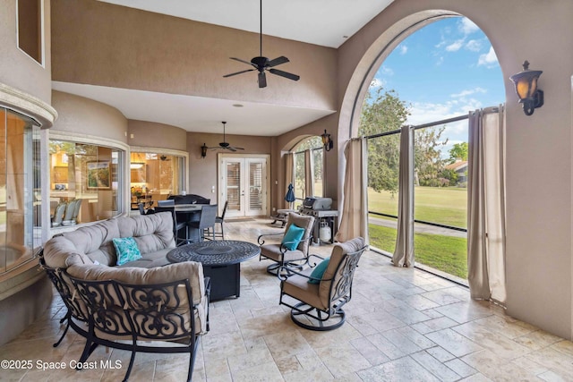 view of patio / terrace with an outdoor living space with a fire pit, area for grilling, a ceiling fan, and french doors