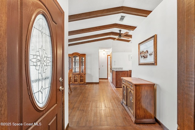 entryway featuring light wood-type flooring and vaulted ceiling with beams