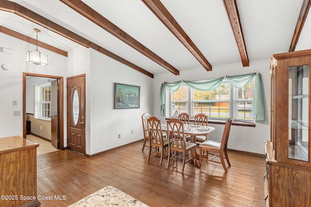 dining area featuring vaulted ceiling with beams and hardwood / wood-style flooring