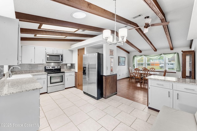 kitchen with sink, hanging light fixtures, stainless steel appliances, and vaulted ceiling with beams