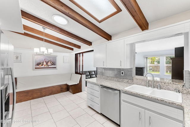 kitchen featuring sink, white cabinetry, stainless steel dishwasher, and vaulted ceiling with beams