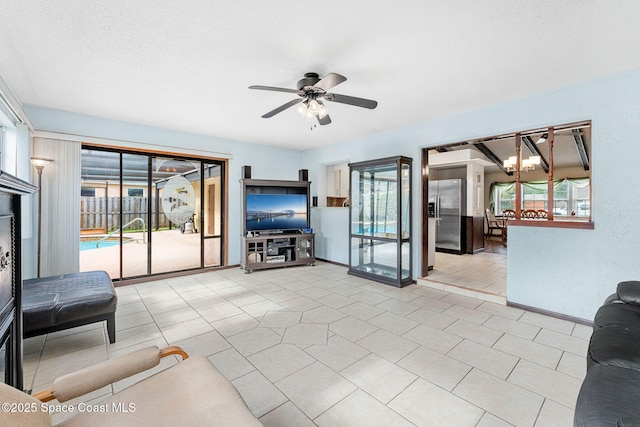 living room featuring light tile patterned floors, ceiling fan with notable chandelier, and a textured ceiling