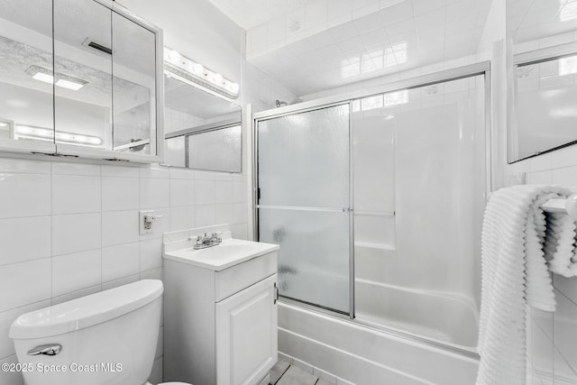 full bathroom with toilet, combined bath / shower with glass door, tile walls, tile patterned floors, and vanity