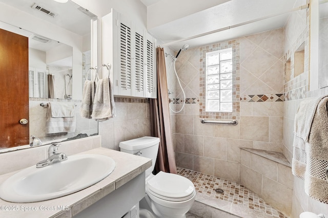 bathroom featuring curtained shower, tile walls, toilet, and vanity