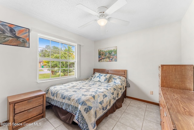 bedroom featuring ceiling fan, a textured ceiling, and light tile patterned floors