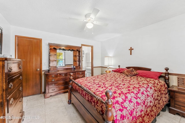 bedroom with a textured ceiling, ceiling fan, and ensuite bath