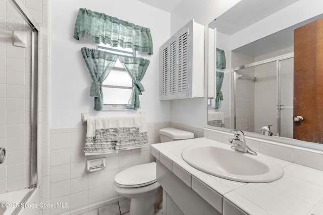 bathroom featuring toilet, vanity, tile walls, and tile patterned floors