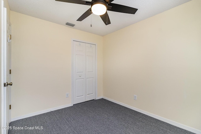 unfurnished bedroom with dark carpet, ceiling fan, and a closet