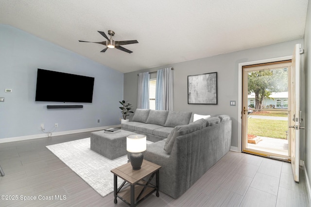 living room with ceiling fan, lofted ceiling, and a textured ceiling