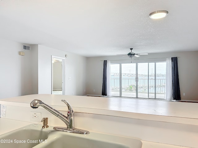 interior space with a textured ceiling, ceiling fan, and sink