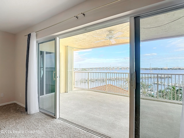 entryway with carpet flooring, ceiling fan, and a water view