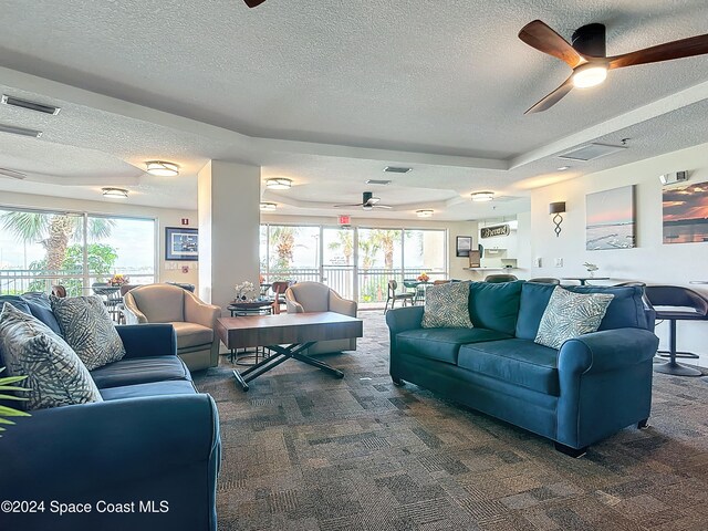 living room featuring a textured ceiling, dark carpet, and plenty of natural light