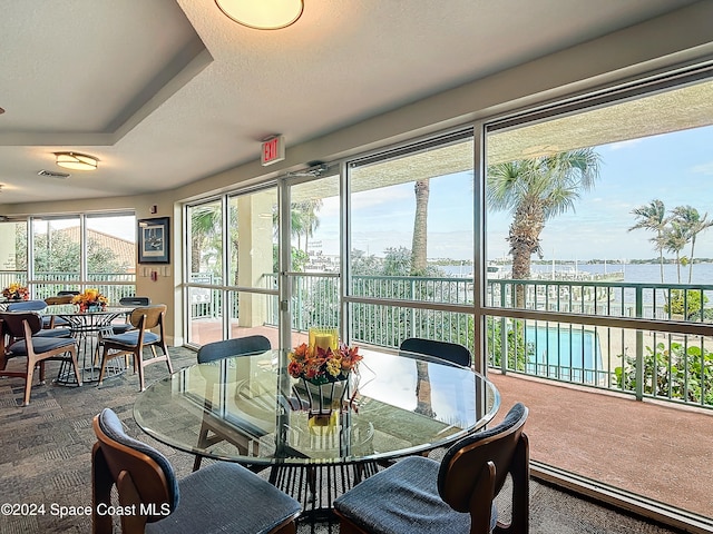 sunroom featuring a tray ceiling and a water view