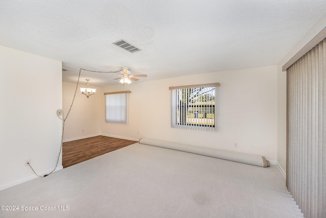 empty room featuring ceiling fan with notable chandelier, wood-type flooring, and a textured ceiling