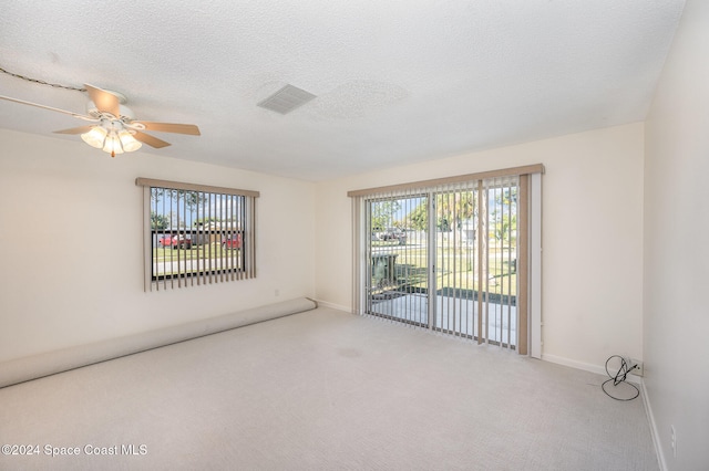 spare room with light carpet, ceiling fan, and a textured ceiling