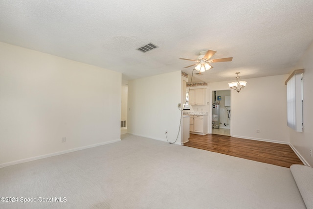 unfurnished living room featuring hardwood / wood-style flooring, ceiling fan with notable chandelier, a textured ceiling, and water heater