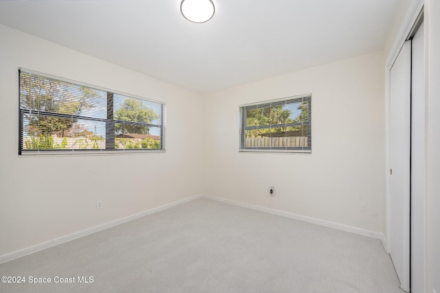 unfurnished bedroom with light carpet and a closet